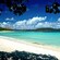 A white sand beach with Guests relaxing and a catamaran close to the shore